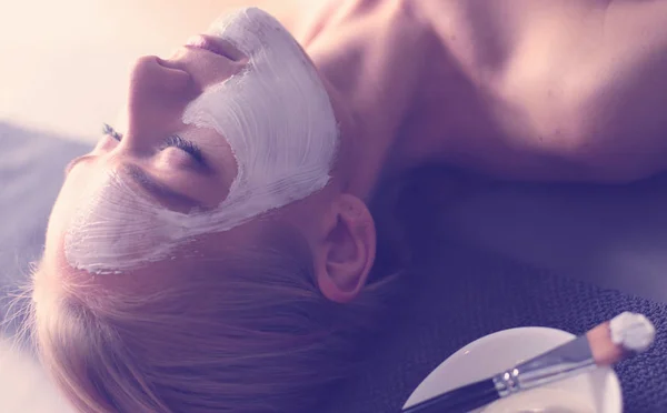 Gezichtsmasker. Mooi jong meisje in spa, schoonheidsspecialist vrouw gezicht masker toe te passen — Stockfoto