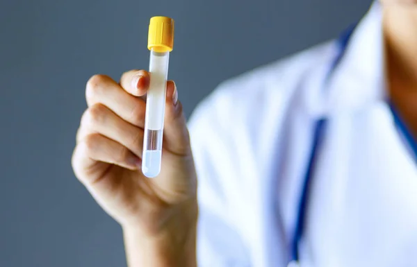 Female medical or research scientist or doctor using looking at a test tube of clear solution in a lab or laboratory. — Stock Photo, Image