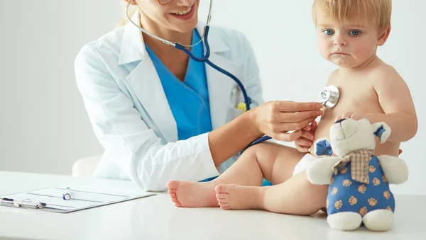 Female doctor is listening kid with a stethoscope in clinic — Stock Photo, Image