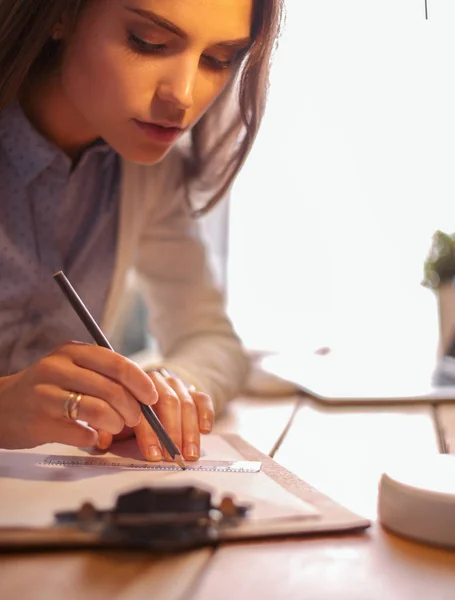 Mujer joven trabajando sentada en un escritorio. Empresaria. Dibujo. Estudiante. Lugar de trabajo. Escritorio. —  Fotos de Stock