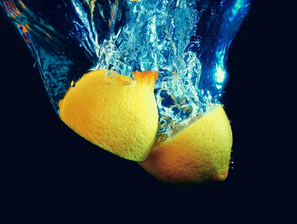 Splashing lemon into fresh water on dark background — Stock Photo, Image