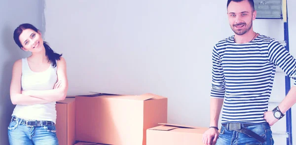 Joven pareja feliz en la habitación con cajas móviles en el nuevo hogar — Foto de Stock