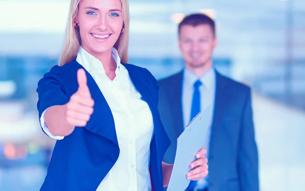 Retrato de la joven mujer de negocios mostrando bien en la oficina con sus colegas en el fondo — Foto de Stock