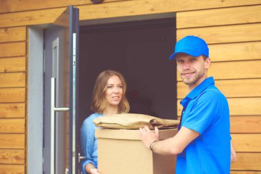 Mavi üniformalı gülümseyen kurye servis konseptine paket kutusu teslim eden teslimatçı. Mavi üniformalı gülümseyen teslimatçı.