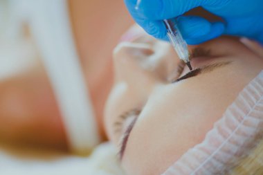 Kaşlar için kalıcı makyaj. Güzellik salonunda kalın kaşlı güzel bir kadın..