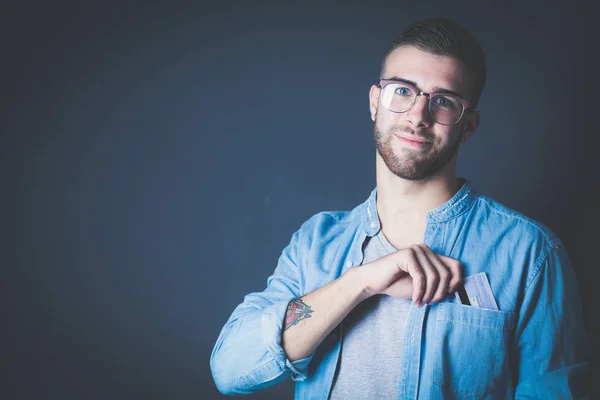 Joven sosteniendo una tarjeta de crédito de pie sobre fondo gris. Joven empresario. —  Fotos de Stock