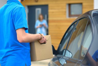Mavi üniformalı gülümseyen kurye servis konseptine paket kutusu teslim eden teslimatçı. Mavi üniformalı gülümseyen teslimatçı.