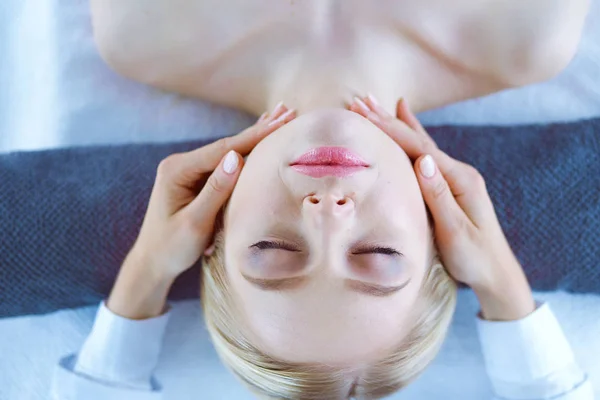 Jovem deitada em uma mesa de massagem, relaxando com os olhos fechados. Mulher. Salão de Spa — Fotografia de Stock