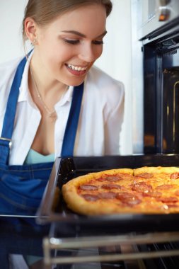 Mutlu genç bayan evde pizza pişiriyor.