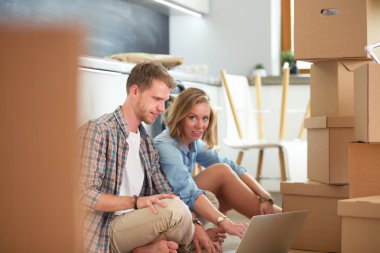 Genç bir çift yeni ev içinde hareket. Oturma ve açma sonra rahatlatıcı. Bir şey üstünde laptop arıyorum. Genç Çift