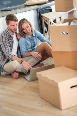Genç bir çift yeni ev içinde hareket. Oturma ve açma sonra rahatlatıcı. Bir şey üstünde laptop arıyorum. Genç Çift.