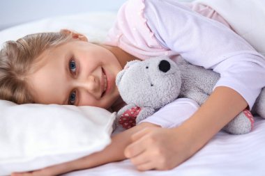 Küçük kız dişçi ofisinde oturuyor.