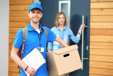 Mavi üniformalı gülümseyen kurye servis konseptine paket kutusu teslim eden teslimatçı. Mavi üniformalı gülümseyen teslimatçı.