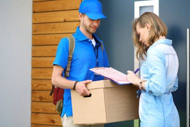 Mavi üniformalı gülümseyen kurye servis konseptine paket kutusu teslim eden teslimatçı. Mavi üniformalı gülümseyen teslimatçı.