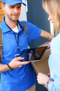 Mavi üniformalı gülümseyen kurye servis konseptine paket kutusu teslim eden teslimatçı. Mavi üniformalı gülümseyen teslimatçı.