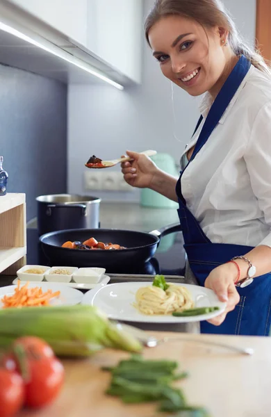 Jovem mulher em pé junto ao fogão na cozinha — Fotografia de Stock