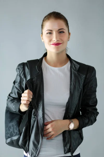 Portrait of beautiful young brunette woman in stylish black jacket on gray. — Stock Photo, Image