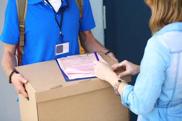 Mavi üniformalı gülümseyen kurye servis konseptine paket kutusu teslim eden teslimatçı. Mavi üniformalı gülümseyen teslimatçı.