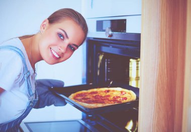 Mutlu genç bayan evde pizza pişiriyor.