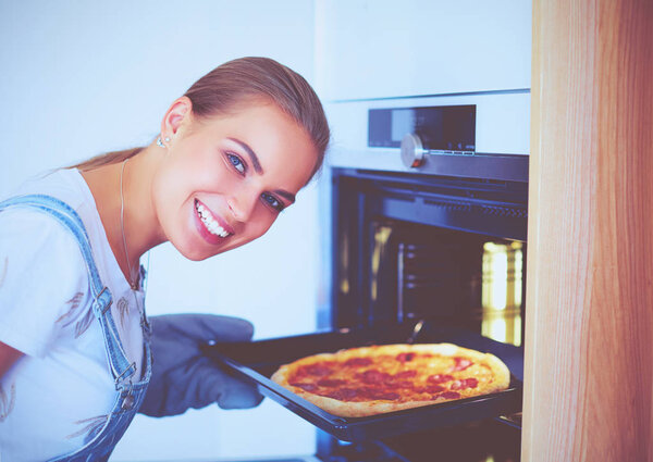 Happy young woman cooking pizza at home