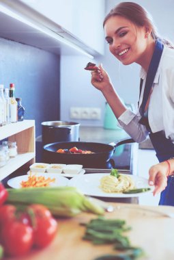 Mutfakta sobanın yanında duran genç bir kadın.