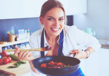 Mutfakta sobanın yanında duran genç bir kadın.
