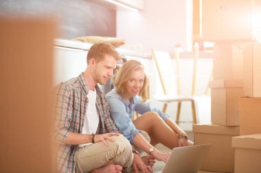 Genç bir çift yeni ev içinde hareket. Oturma ve açma sonra rahatlatıcı. Bir şey üstünde laptop arıyorum. Genç Çift