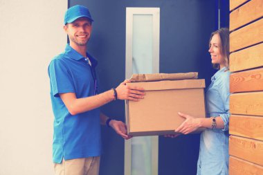 Mavi üniformalı gülümseyen kurye servis konseptine paket kutusu teslim eden teslimatçı. Mavi üniformalı gülümseyen teslimatçı.
