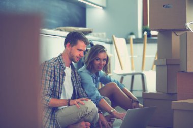 Genç bir çift yeni ev içinde hareket. Oturma ve açma sonra rahatlatıcı. Bir şey üstünde laptop arıyorum. Genç Çift