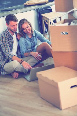 Genç bir çift yeni ev içinde hareket. Oturma ve açma sonra rahatlatıcı. Bir şey üstünde laptop arıyorum. Genç Çift