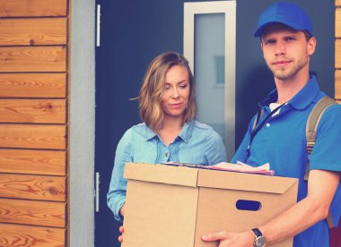 Mavi üniformalı gülümseyen kurye servis konseptine paket kutusu teslim eden teslimatçı. Mavi üniformalı gülümseyen teslimatçı.