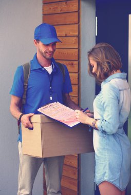 Mavi üniformalı gülümseyen kurye servis konseptine paket kutusu teslim eden teslimatçı. Mavi üniformalı gülümseyen teslimatçı.