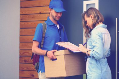 Mavi üniformalı gülümseyen kurye servis konseptine paket kutusu teslim eden teslimatçı. Mavi üniformalı gülümseyen teslimatçı.