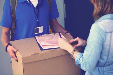 Mavi üniformalı gülümseyen kurye servis konseptine paket kutusu teslim eden teslimatçı. Mavi üniformalı gülümseyen teslimatçı.