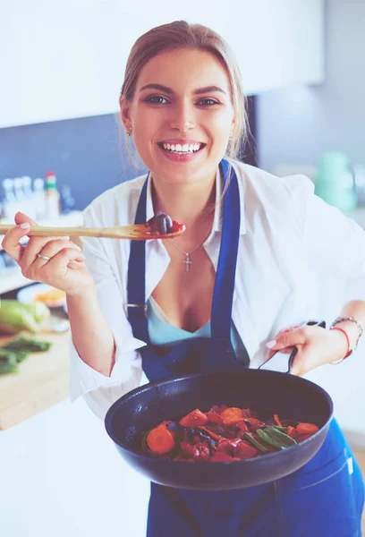 Młoda kobieta stojąca przy piecu w kuchni — Zdjęcie stockowe