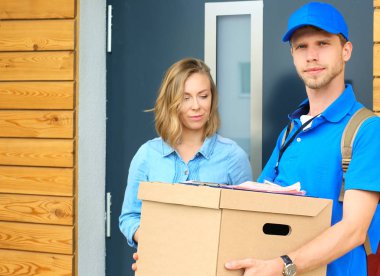 Mavi üniformalı gülümseyen kurye servis konseptine paket kutusu teslim eden teslimatçı. Mavi üniformalı gülümseyen teslimatçı.
