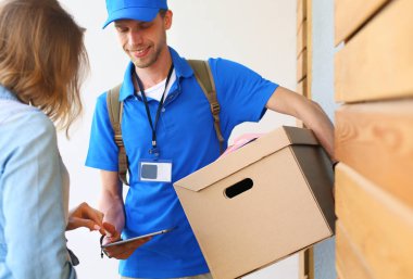 Mavi üniformalı gülümseyen kurye servis konseptine paket kutusu teslim eden teslimatçı. Mavi üniformalı gülümseyen teslimatçı.