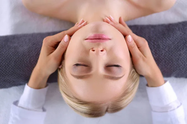 Mujer joven acostada en una mesa de masaje, relajándose con los ojos cerrados. Una mujer. Salón de spa —  Fotos de Stock