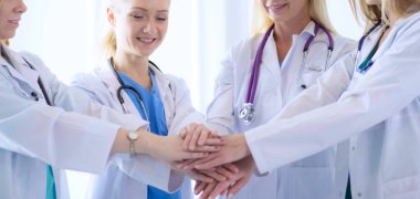 Doktorlar ve hemşireler tıbbi bir ekipte el ele tutuşuyorlar.