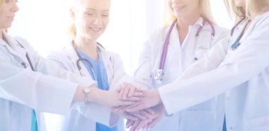 Doktorlar ve hemşireler tıbbi bir ekipte el ele tutuşuyorlar.