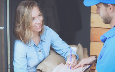 Mavi üniformalı gülümseyen kurye servis konseptine paket kutusu teslim eden teslimatçı.