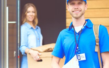 Mavi üniformalı gülümseyen kurye servis konseptine paket kutusu teslim eden teslimatçı. Mavi üniformalı gülümseyen teslimatçı.