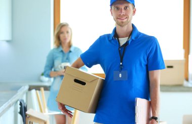 Mavi üniformalı gülümseyen kurye servis konseptine paket kutusu teslim eden teslimatçı.