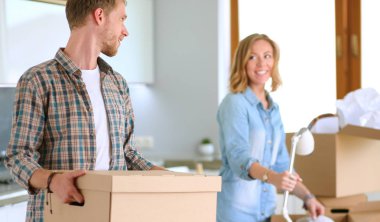 Genç bir çift yeni evinde büyük bir karton kutu taşıyor. Taşınıyorlar.