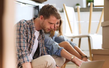 Genç bir çift yeni ev içinde hareket. Oturma ve açma sonra rahatlatıcı. Bir şey üstünde laptop arıyorum. Genç Çift