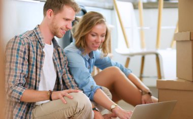 Genç bir çift yeni ev içinde hareket. Katta oturan ve açma sonra rahatlatıcı. Bir şey üstünde laptop arıyorum