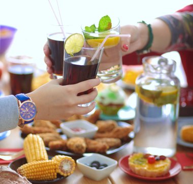 Ahşap masada otururken birlikte yemek yiyen bir grup insanın üst düzey görüntüsü. Masada yemek var. İnsanlar fast food yiyor..