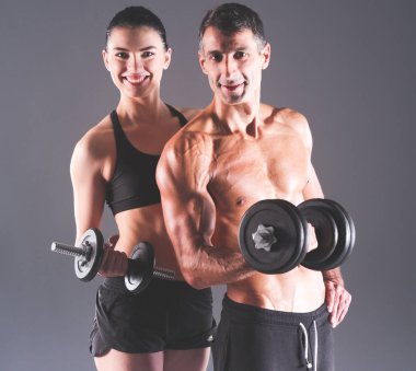Atletik erkek ve kadın ile bir dumbells. Kişisel fitness eğitmeni. Kişisel eğitim.
