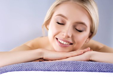 Masaj masasında uzanmış gözleri kapalı rahatlayan genç bir kadın. - Kadın. Spa salonu