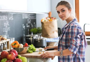 Cep telefonu ayakta modern mutfak kullanan kadın.